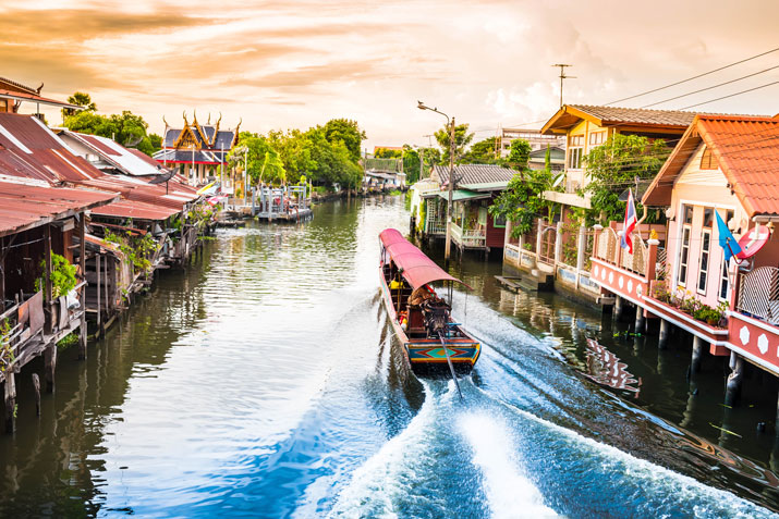 Mit dem Longtailboot auf den Wasserstraßen in Bangkok vorbei an Tempeln und Stelzenhäusern.