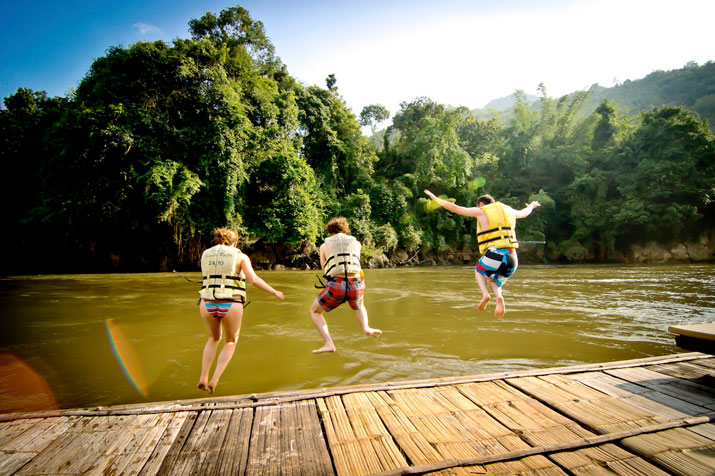Touristen springen auf ihrer Thailand Rundreise in den River Kwai in Kanchanaburi.