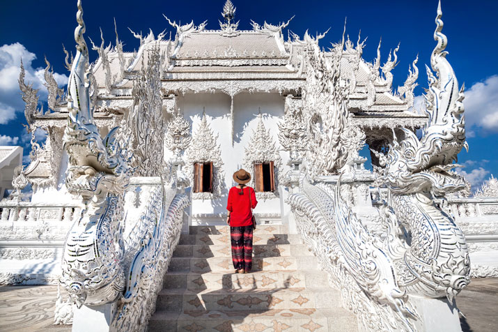 Eine Touristin besucht auf ihrer Rundreise ab Bangkok in Chiang Rai den Wat Rong Khun, besser bekannt als der Weiße Tempel.