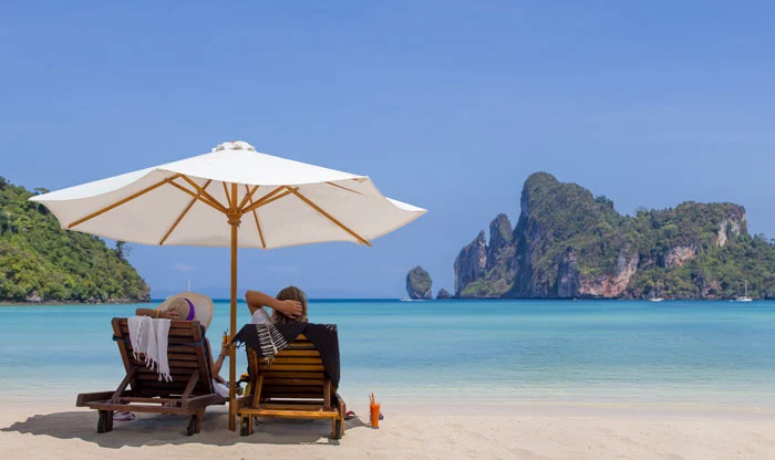 Touristen relaxen in ihrem Thailand Urlaub am Strand in Krabi.